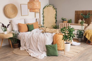 Rahat yatağı, çekmeceleri ve bitkileri olan rahat bir yatak odası.