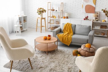 Sonbahar dekoru, kanepesi ve koltuğu olan bir oturma odası.