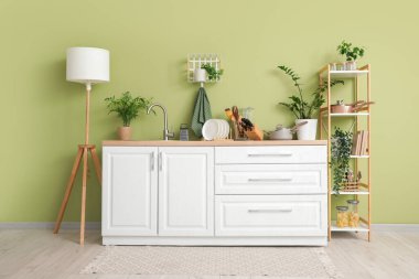 Mutfağın içinde tezgah, raf ünitesi ve mutfak gereçleri var.