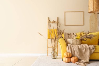 Sarı kanepe, balkabakları, otlar ve ekoseler sonbaharda oturma odasının içinde.