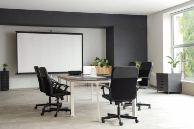 Masa ve projektör ekranlı konferans salonunun içi