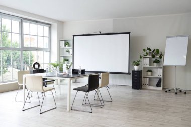 Projektör ekranı ve toplantı tablosu olan ofis içi