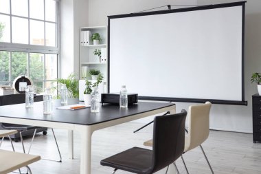 Projektör ekranı ve toplantı tablosu olan ofis içi