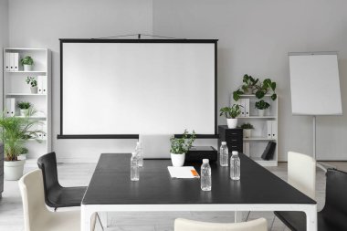 Projektör ekranı ve toplantı tablosu olan ofis içi