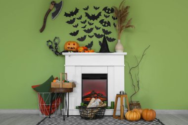 Cadılar Bayramı için dekore edilmiş şömine oturma odasındaki yeşil duvarın yanında.