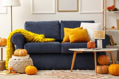 Oturma odasının içi kanepe, masa ve balkabağı dolu.