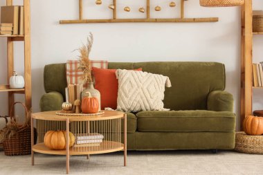 Sonbahar dekoru, kanepesi ve masası olan aydınlık oturma odasının içinde.