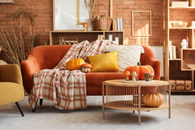 Sonbahar dekoru, kırmızı kanepesi ve masası olan rahat bir oturma odası.