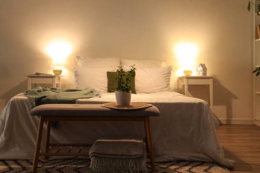 Sıcak yataklı, çiçekli ve parlak lambalı karanlık yatak odasının içi.