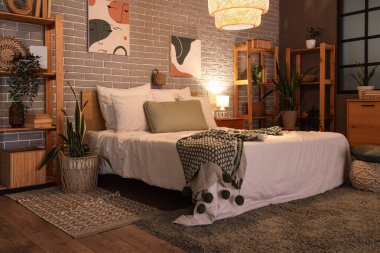 Yatak odasının içinde yatak odası, raf üniteleri, komodin ve parlayan lamba.