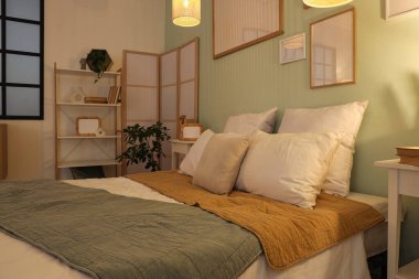 Raflama ünitesi, katlanır ekran ve yatak odasının içinde rahat bir yatak.