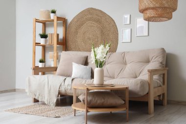 Rahat bir kanepe, çiçekli kahve masası ve oturma odasının iç tarafında raf ünitesi.