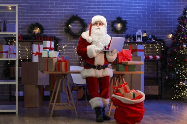 Noel Baba dizüstü bilgisayarı, çantası ve hediye kutuları postanede.