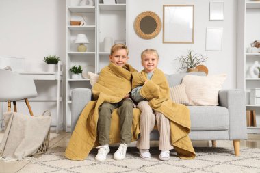 Ekoseli çocuklar evdeki kanepede oturuyor.