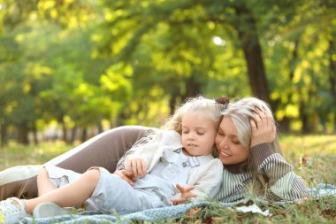 Sonbahar günü annesiyle birlikte parkta yatan küçük bir kız.