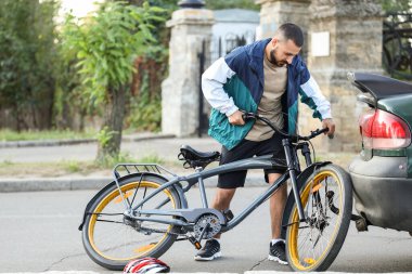 Genç erkek bisikletçi açık havada arabaya çarptı.