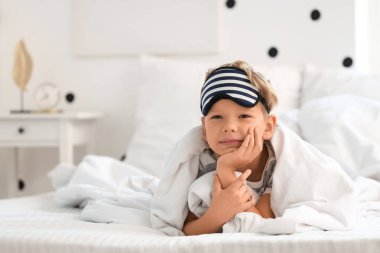 Pijamalı, tatlı, mutlu bir çocuk. Evde, yatağında maske takıyor.