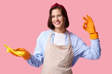 Pembe arka planda paçavraları olan güzel bir ev hanımı.