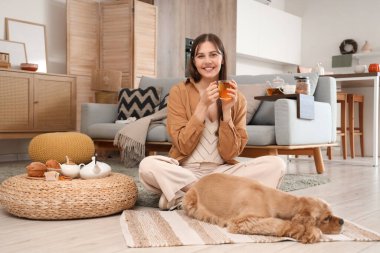 Güzel, genç, mutlu bir kadın ve evde oturmuş yeşil çay içen sevimli Cocker Spaniel köpeği.