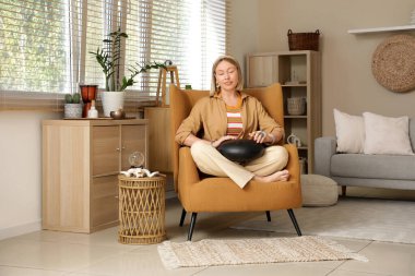 Evdeki koltukta glukofon çalan güzel bir kadın.