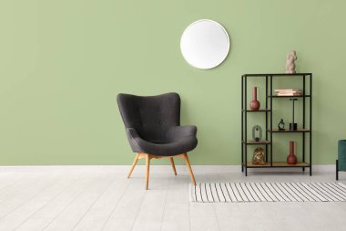 Koltuk, raf ünitesi ve ayna oturma odasında yeşil duvarda.