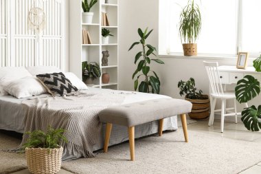 Yatak odasının içinde rahat bir yatak, raflar ve ev bitkileri var.