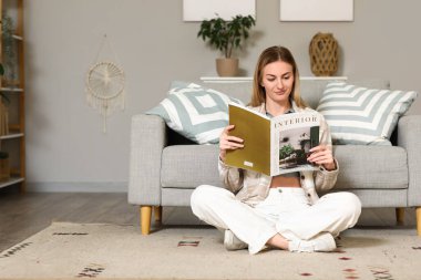 Young woman reading magazine on carpet at home