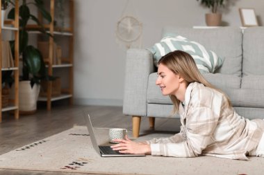 Evde dizüstü bilgisayar kullanan genç bir kadın.