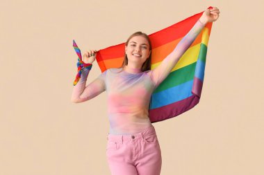 Bej arka planda LGBT bayrağı taşıyan gülümseyen genç kadın