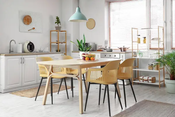 Yemek masası, sandalye ve lambalı şık bir mutfak.