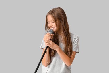 Gri arka planda modern mikrofonu olan tatlı bir kız.