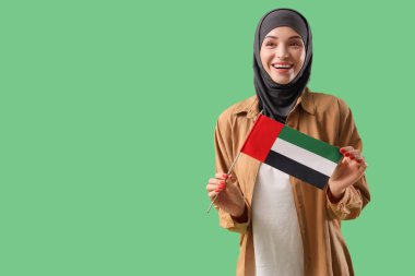 Yeşil arka planda BAE bayrağı olan genç Müslüman kadın.