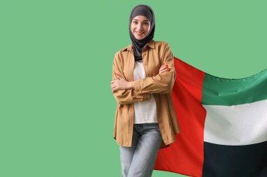 Yeşil arka planda BAE bayrağı olan genç Müslüman kadın.