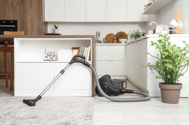 Elektrik süpürgesi, masa ve tezgahlı mutfağın içi.