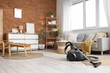 Elektrik süpürgesi, kanepe ve çekmeceleri olan bir oturma odası.