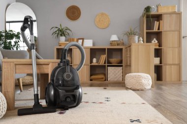 Oturma odasındaki kahve masasının yanındaki elektrikli süpürge.