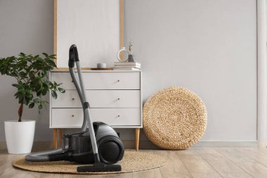 Elektrik süpürgesi, çekmecesi ve puf olan oturma odasının içinde.