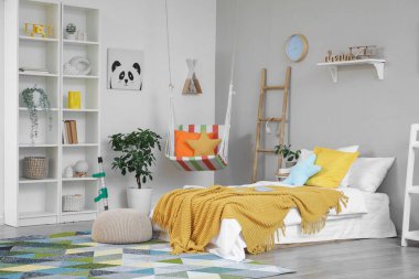 İçinde yatak, raf ve sallanan sandalye olan hafif çocuk odası.