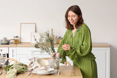 Güzel genç bir kadın, okaliptüs dallarını vazoya koyuyor. Hafif mutfakta zarif bir şekilde servis edilen masaya.