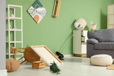 Depremden sonra mobilyaların ve gri kanepenin devrildiği dağınık bir oturma odası.