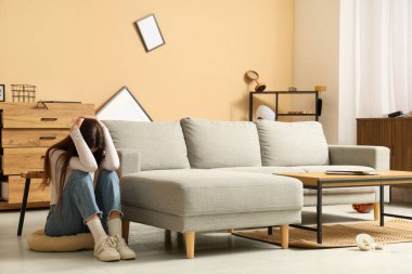 Deprem sırasında oturma odasındaki kanepede başını örten korkmuş genç kadın.