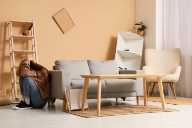 Deprem sırasında oturma odasındaki kanepede başını örten korkmuş genç kadın.