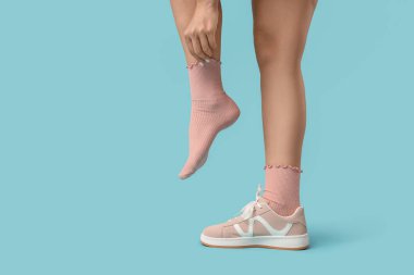 Mavi arka planda şık spor ayakkabılı kadın.