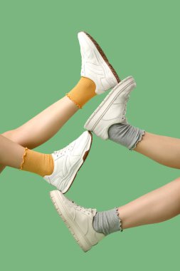 Yeşil arka planda şık spor ayakkabılı kadınların bacakları