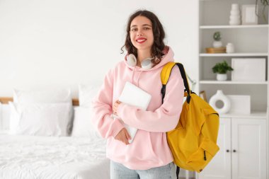 Yatak odasında sırt çantası ve dizüstü bilgisayarı olan Hintli bir kız öğrenci.