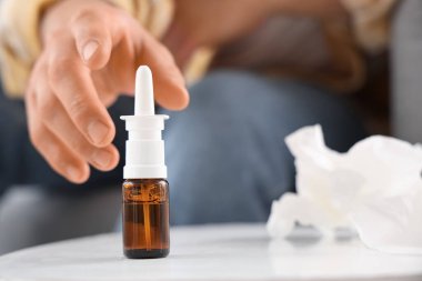 Hasta genç adam evdeki masadan burun damlası alıyor, yakın plan.