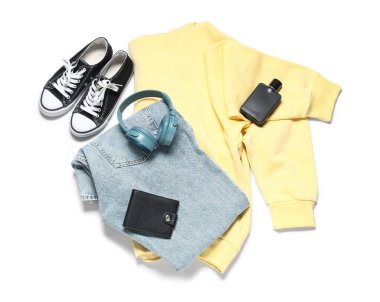 Beyaz arka planda şık erkek kıyafetleri, ayakkabıları, aksesuarları ve modern kulaklıkları olan kompozisyon