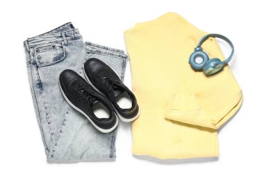 Beyaz arka planda şık erkek kıyafetleri, ayakkabıları ve modern kulaklıkları olan kompozisyon