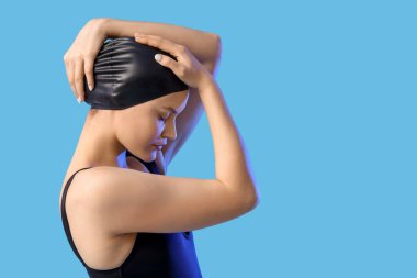 Dişi yüzücü mavi arka plana şapka takıyor