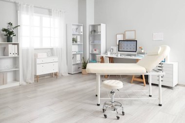 Doktorun iş yeri, raf üniteleri ve kanepesi olan sağlık bürosu.